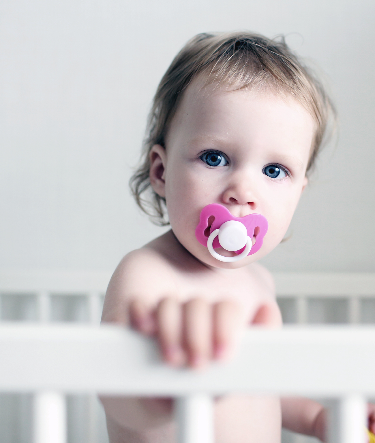Cute little 1 years baby girl with dummy in white bed
